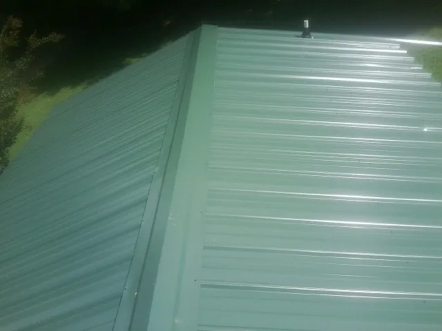 New green metal panels meeting at the ridge of a roof — Flat Roof Repair work by our crew in Avon